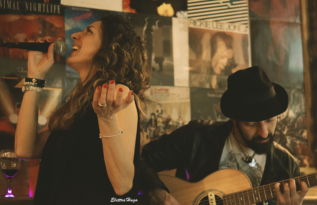 Mirco playing acoustic guitar alongside a singer in an intimate live setting